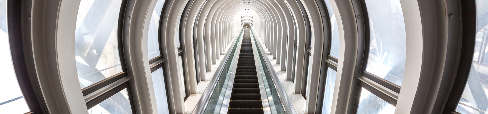 Schmaler langer Tunnel mit Rolltreppe mittig.